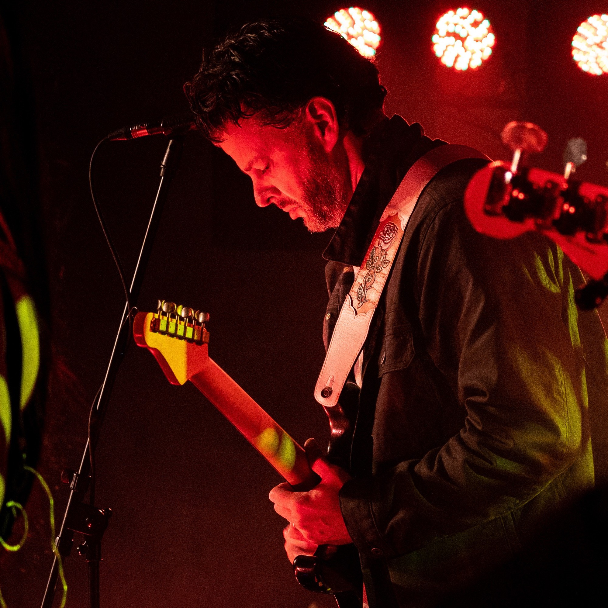 Matt Dorsey playing electric guitar under red stage lights
